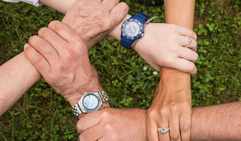5 hands holding each hand at the wrist forming a cirlce