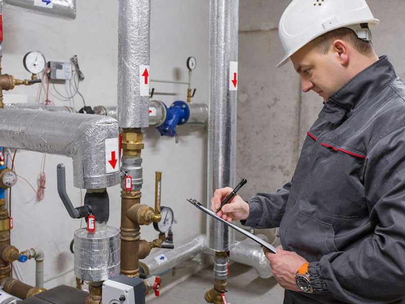 Plumber checking a list, standing near water valve shutoff